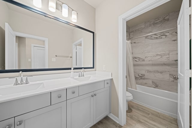 bathroom featuring double vanity, a sink, toilet, and wood finished floors