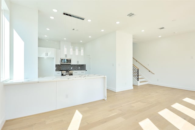 kitchen featuring light stone counters, visible vents, light wood-style floors, white cabinets, and appliances with stainless steel finishes