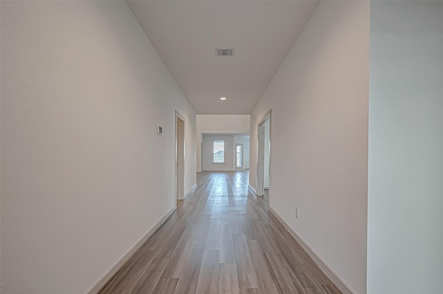 corridor featuring light wood-type flooring, visible vents, and baseboards