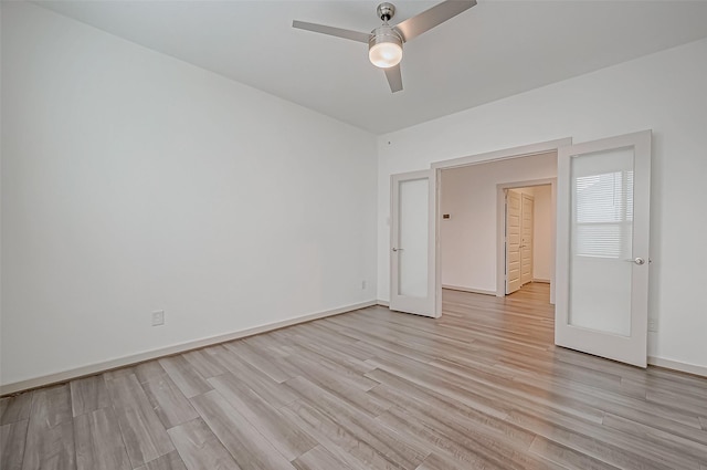 unfurnished room with ceiling fan, light wood finished floors, and baseboards