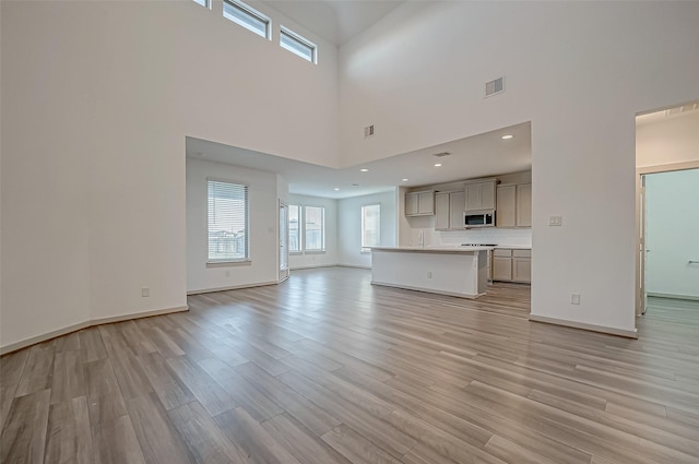 unfurnished living room featuring light wood-type flooring, visible vents, and baseboards