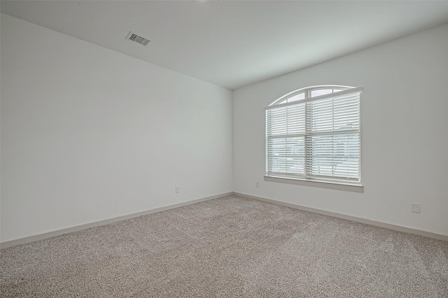 empty room featuring baseboards, visible vents, and light colored carpet