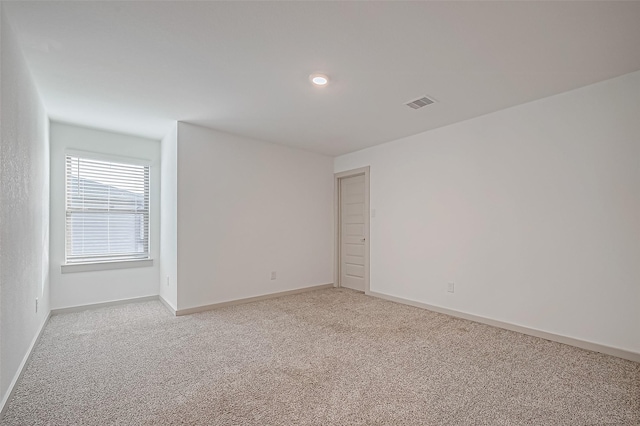 spare room featuring baseboards, visible vents, and light colored carpet