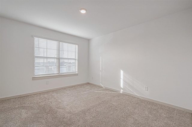 unfurnished room featuring light colored carpet and baseboards