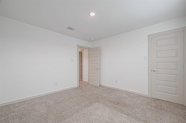 unfurnished room with visible vents, light carpet, and baseboards