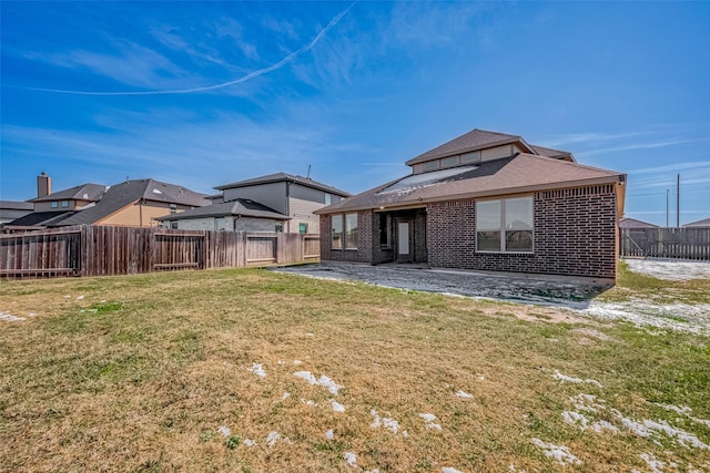 rear view of property featuring a patio area, brick siding, a yard, and a fenced backyard