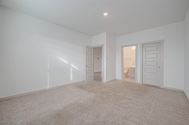 unfurnished bedroom with recessed lighting, baseboards, ensuite bathroom, and light colored carpet