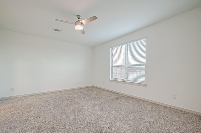 carpeted spare room featuring baseboards, visible vents, and ceiling fan