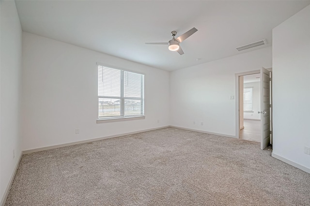 carpeted empty room with baseboards, visible vents, and a ceiling fan