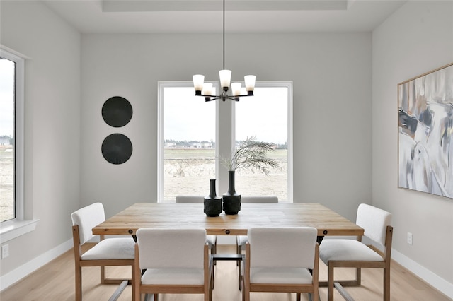 dining area with a healthy amount of sunlight, light wood finished floors, and a notable chandelier