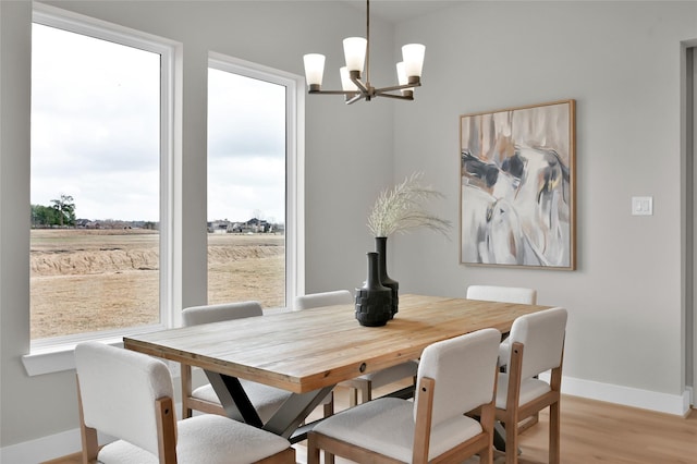 dining area featuring light wood finished floors, baseboards, and an inviting chandelier