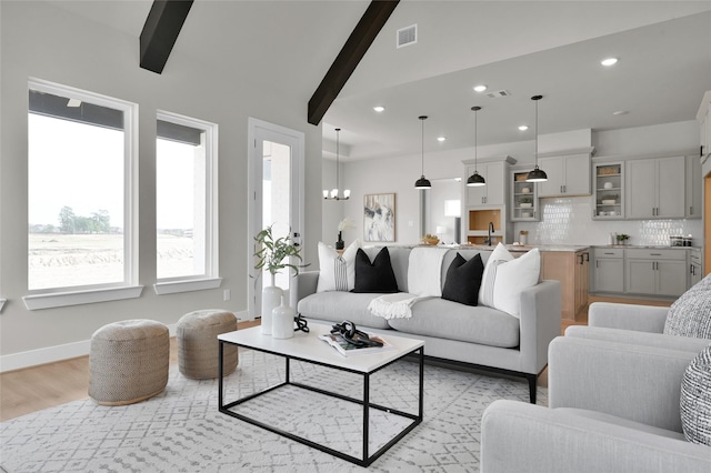 living area featuring light wood-type flooring, baseboards, visible vents, and a chandelier