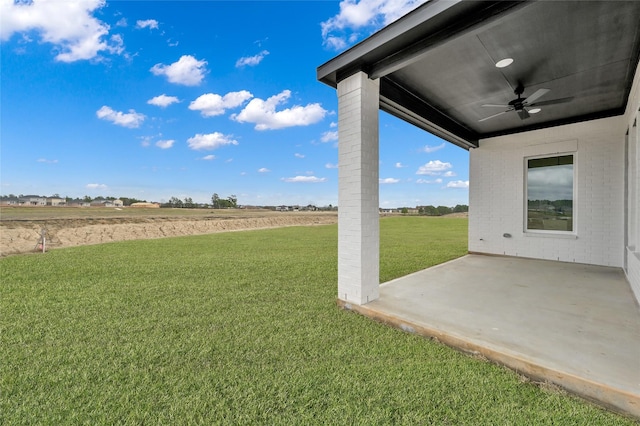 view of yard featuring ceiling fan, a rural view, and a patio