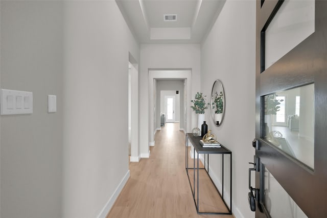 hallway with light wood-type flooring, baseboards, and visible vents