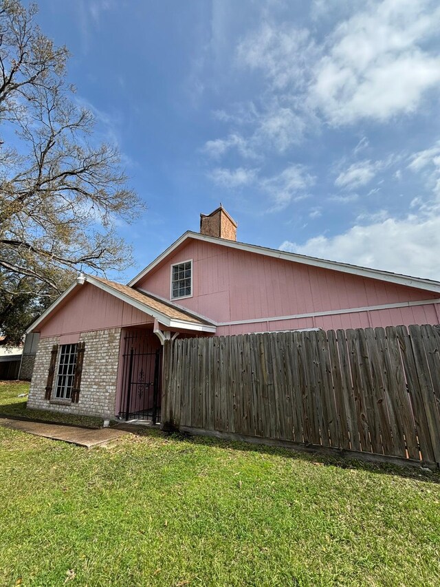 12347 W Village Dr Unit D, Houston, TX 77039 - view of home's exterior featuring brick siding, a lawn, a chimney, and fence