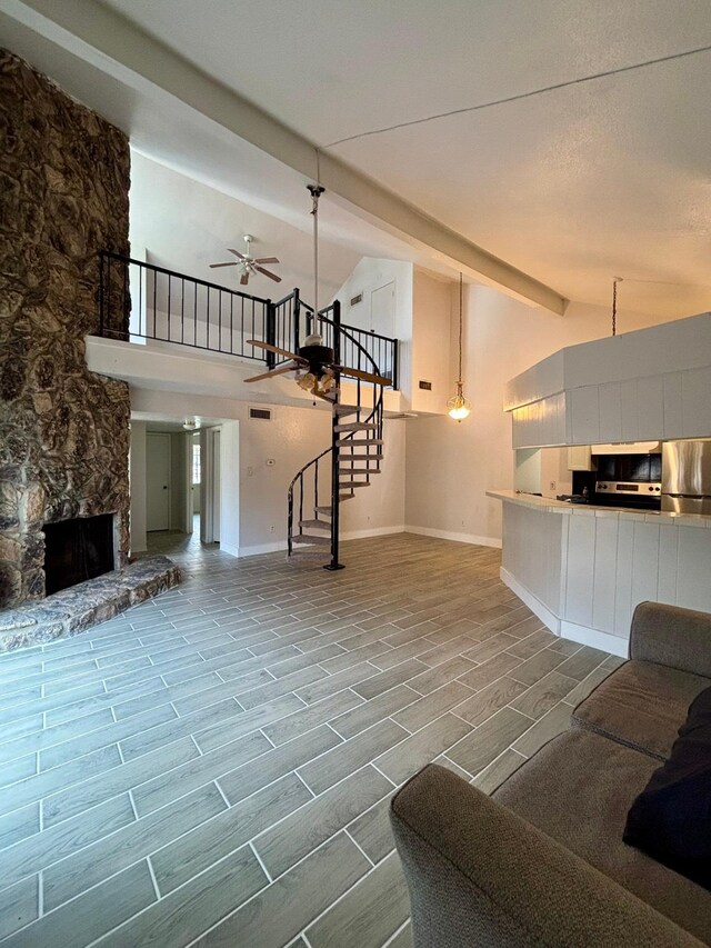 unfurnished living room featuring baseboards, ceiling fan, stairs, wood finish floors, and a fireplace