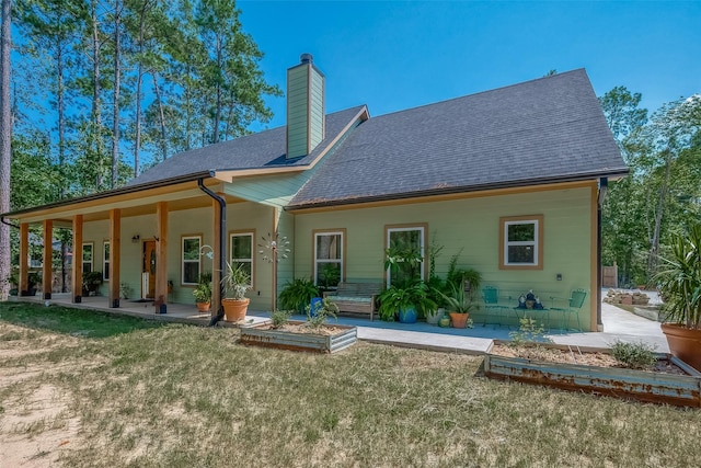 back of house featuring a shingled roof, a yard, and a chimney