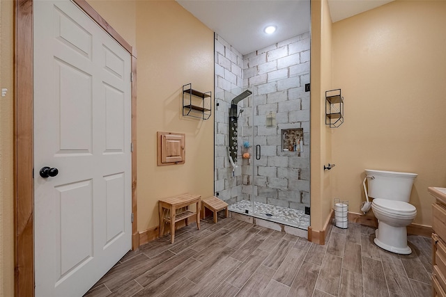 bathroom featuring toilet, a shower stall, baseboards, and wood finish floors