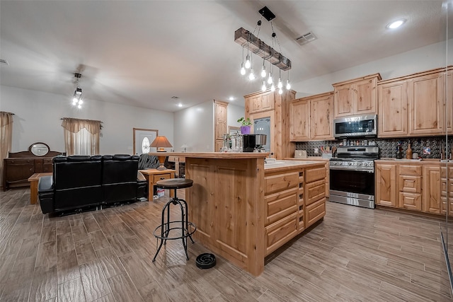 kitchen with stainless steel appliances, tasteful backsplash, visible vents, light wood-style floors, and a kitchen breakfast bar