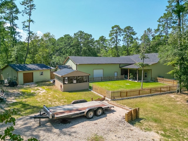 view of front of home with a front lawn, fence, a detached garage, and an outdoor structure