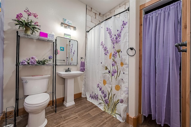 bathroom featuring wood tiled floor, a shower with curtain, baseboards, and toilet