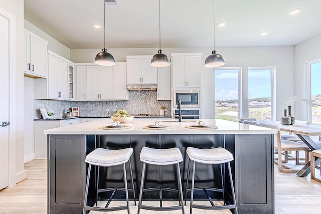 141 Peninsula Point Dr, Montgomery, TX 77356 - kitchen with under cabinet range hood, built in microwave, backsplash, white cabinets, and recessed lighting