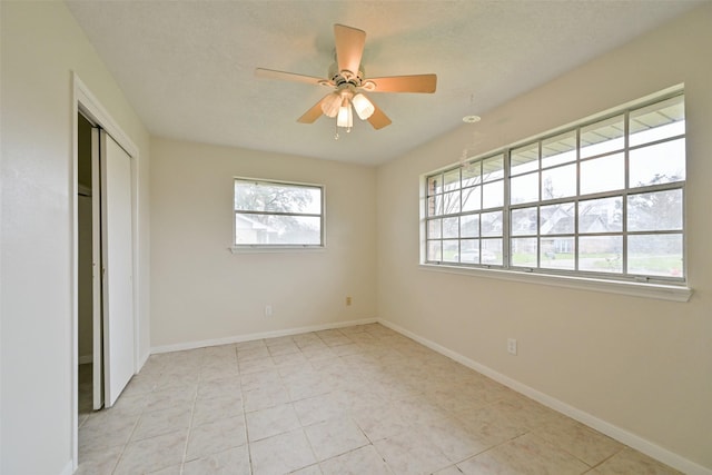 spare room featuring light tile patterned flooring, a ceiling fan, and baseboards