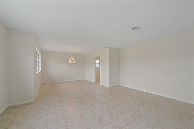 unfurnished room with a chandelier, light tile patterned floors, visible vents, and baseboards