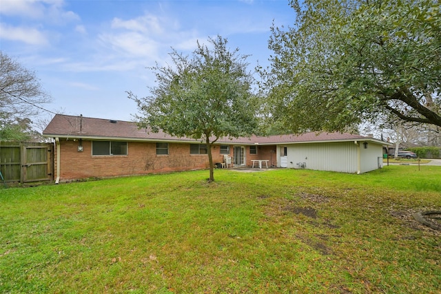 back of house featuring brick siding, a yard, fence, and a patio