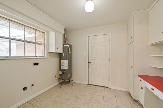 laundry room with water heater, cabinet space, baseboards, and light tile patterned flooring