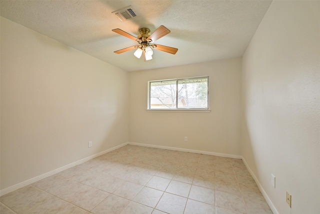 empty room featuring a ceiling fan, visible vents, a textured ceiling, and baseboards