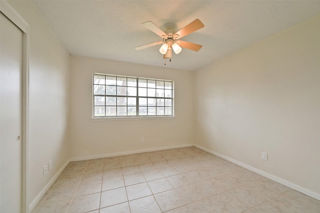 unfurnished room featuring light tile patterned flooring, ceiling fan, and baseboards