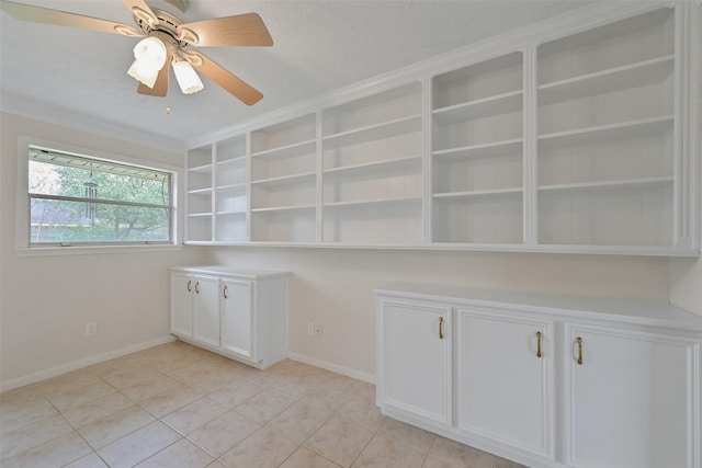 interior space featuring light tile patterned floors, ceiling fan, baseboards, and a textured ceiling