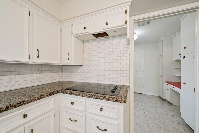 kitchen featuring black electric stovetop, white cabinets, and dark stone counters