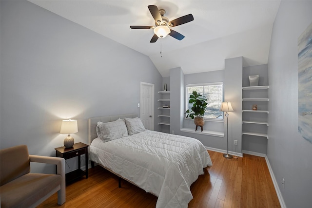 bedroom featuring a ceiling fan, baseboards, vaulted ceiling, and hardwood / wood-style floors