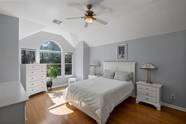 bedroom featuring baseboards, visible vents, hardwood / wood-style flooring, ceiling fan, and vaulted ceiling
