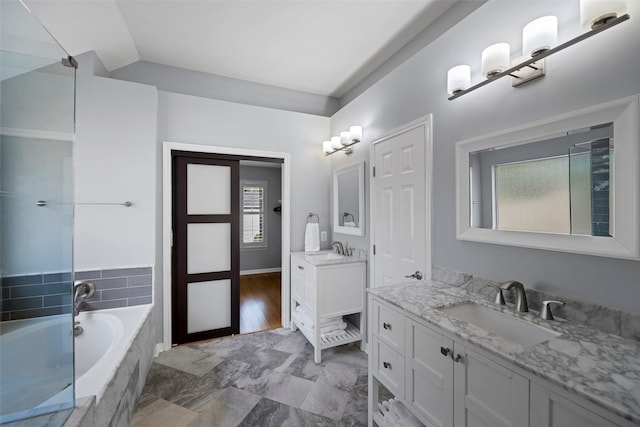 full bath with lofted ceiling, two vanities, a sink, and a garden tub