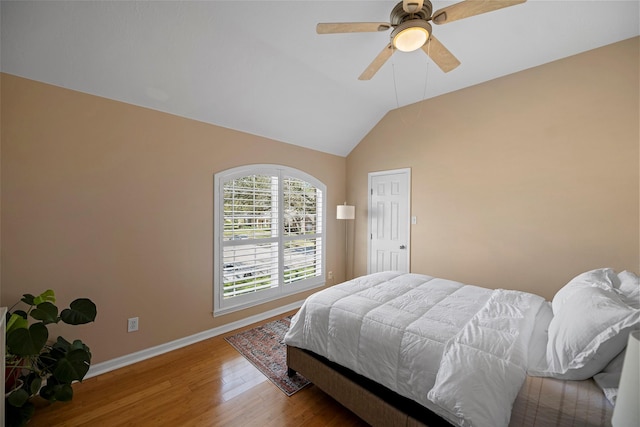 bedroom featuring a ceiling fan, baseboards, vaulted ceiling, and wood finished floors