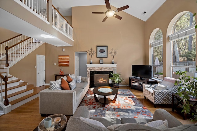 living area featuring stairs, a fireplace, wood finished floors, and visible vents