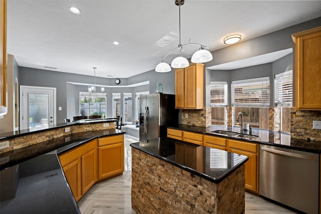 kitchen featuring dark stone counters, stainless steel appliances, tasteful backsplash, and a sink