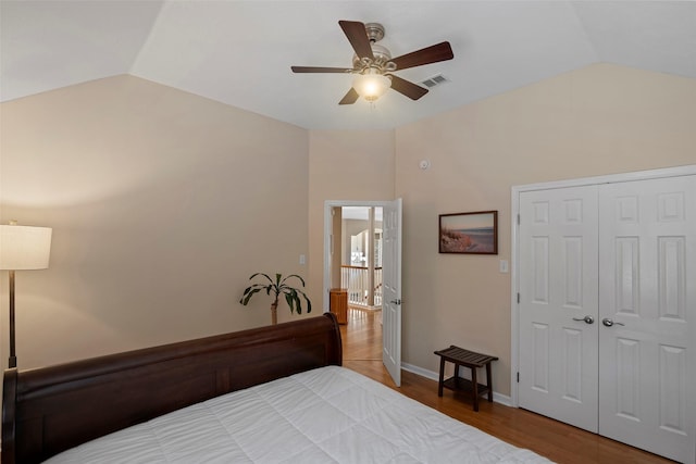 bedroom with visible vents, ceiling fan, wood finished floors, vaulted ceiling, and a closet