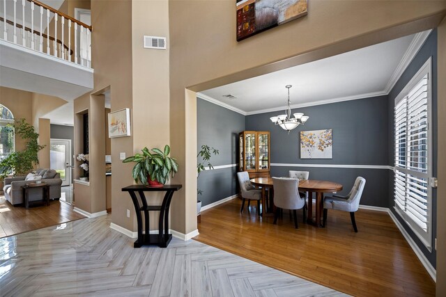 dining room featuring baseboards, visible vents, ornamental molding, an inviting chandelier, and a high ceiling