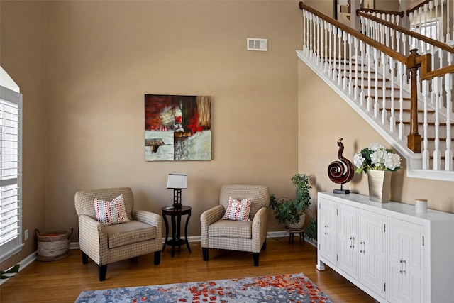 living area featuring baseboards, stairs, visible vents, and wood finished floors