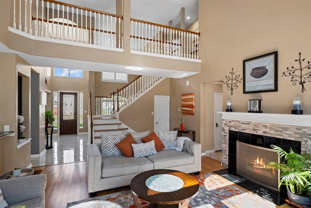 living room featuring baseboards, hardwood / wood-style flooring, a high ceiling, stairs, and a fireplace