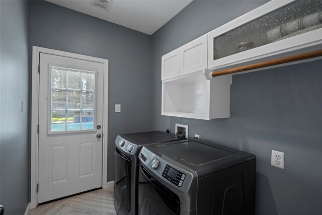 laundry area featuring washer and dryer, cabinet space, visible vents, and baseboards