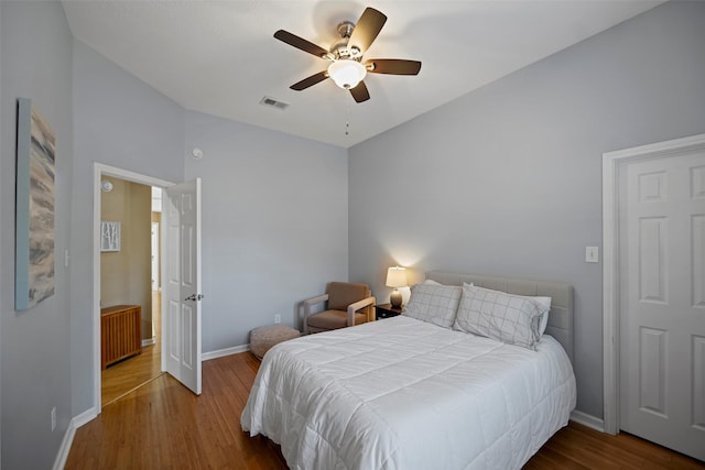 bedroom with radiator, visible vents, ceiling fan, wood finished floors, and baseboards