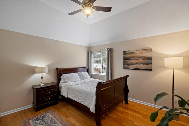 bedroom with a ceiling fan, vaulted ceiling, baseboards, and wood finished floors