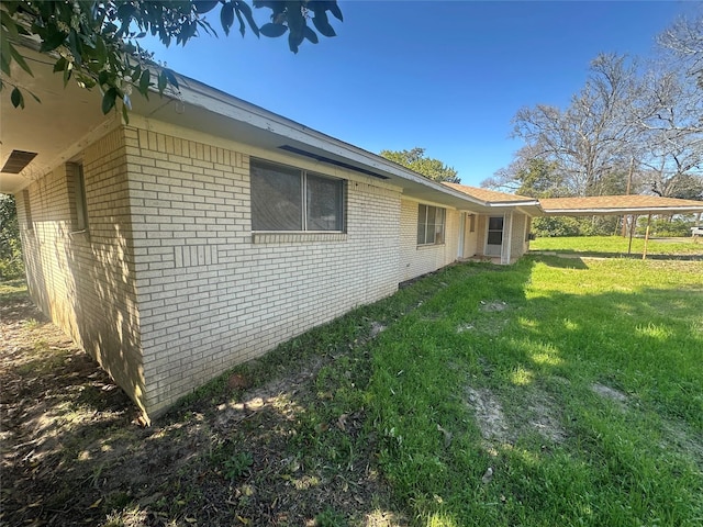 view of side of home with brick siding and a yard