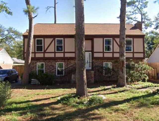 view of front of house featuring brick siding, a chimney, a front lawn, and stucco siding