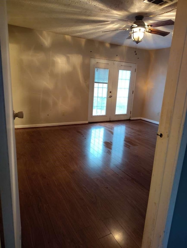 unfurnished room featuring french doors, dark wood-style flooring, a ceiling fan, and baseboards